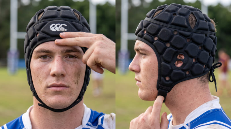 Close-up photograph demonstrating the perfect 3-point fit check of a rugby headguard on a player's head.