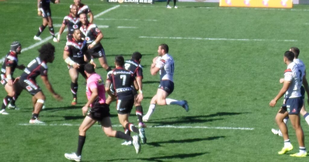 Sydney Roosters player running the ball against the Warriors in an NRL match
