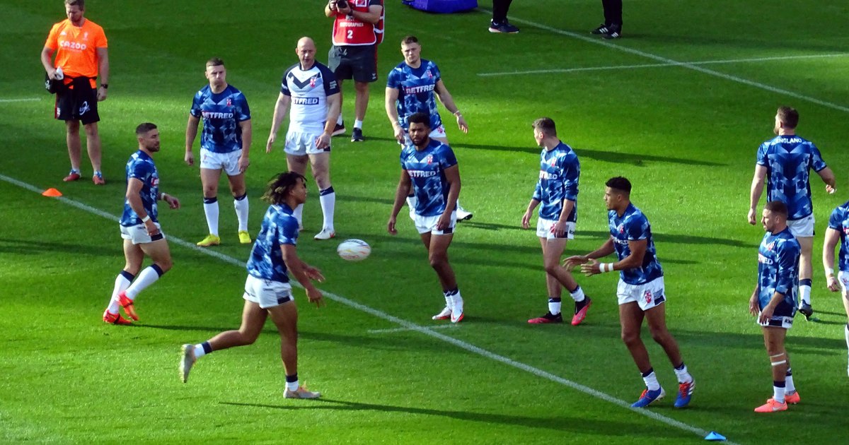 England rugby league players in blue training tops warming up on the pitch