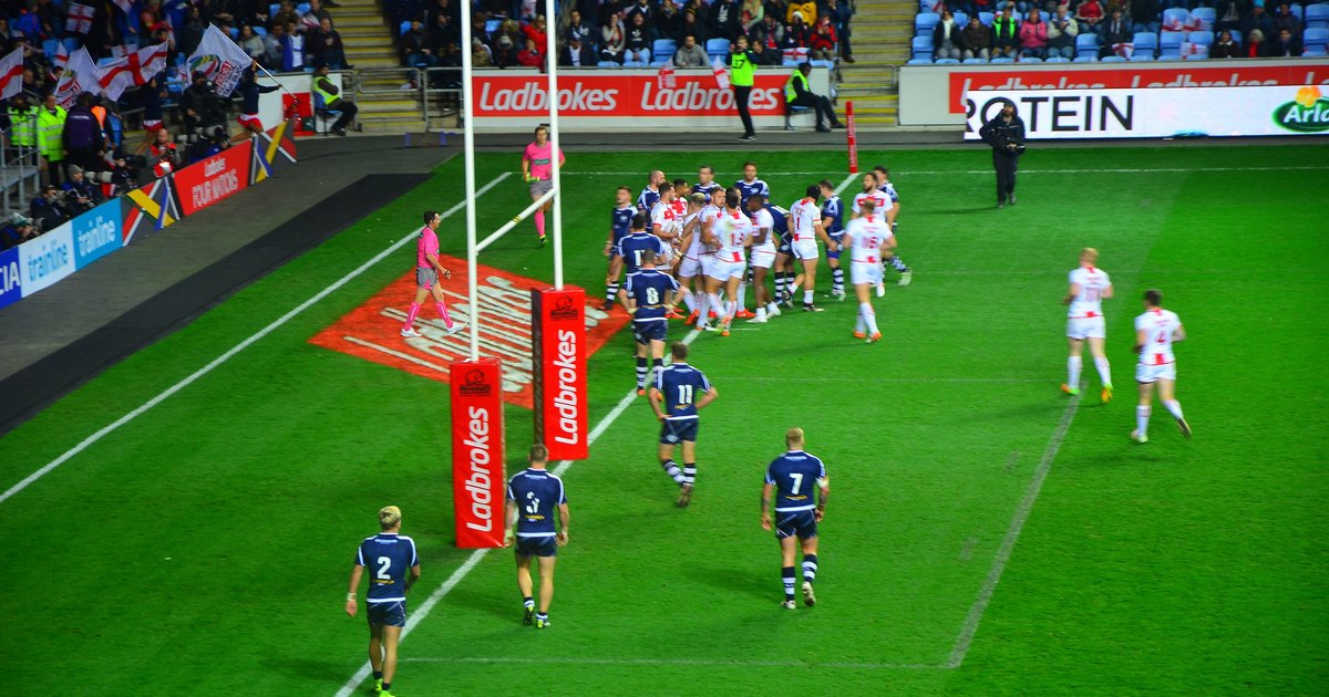 England rugby league players in white attacking against Scotland in navy near the try line