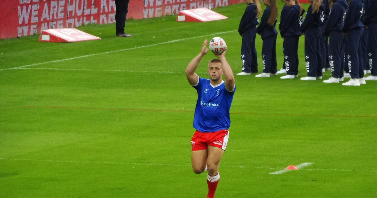 Mikey Lewis throwing a ball in the air during a warm-up on a rugby pitch