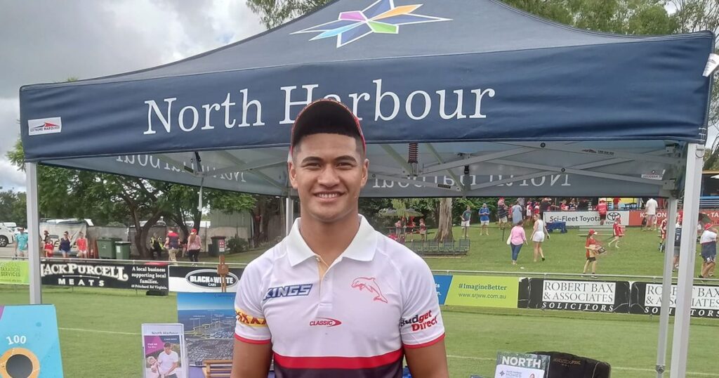Isaiya Katoa in a white Dolphins shirt standing at a community rugby league event