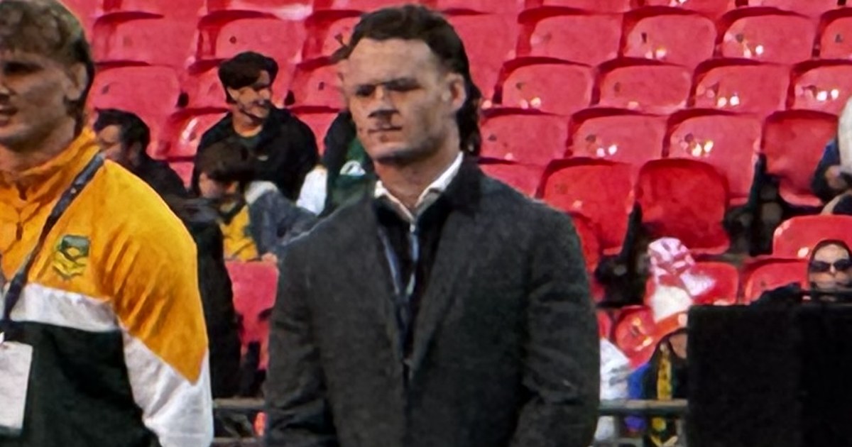 Ethan Strange in a dark suit standing pitchside at Wembley with Australian staff