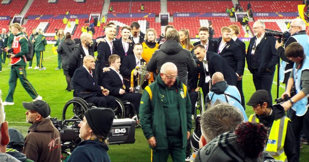 England wheelchair rugby league players and staff celebrating on the pitch at Old Trafford